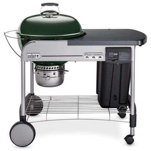 A Weber Performer Deluxe Green Charcoal Grill, green dome lid, silver prep table, black storage container, and attached wheels for mobility, against a white background.