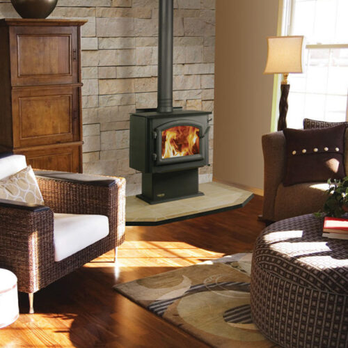 4300 Millennium standard wood stove by Quadra-Fire against a tan stone wall of a living room with hearth pad