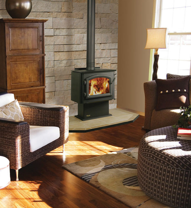 4300 Millennium standard wood stove by Quadra-Fire against a tan stone wall of a living room with hearth pad