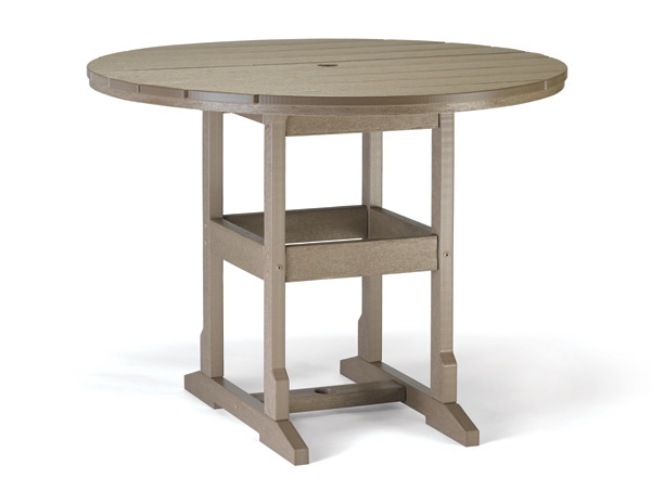 A round, wooden outdoor table from the Counter Collection with a central hole for an umbrella, featuring sturdy leg supports and a lower shelf. The table is made from wood with a muted, natural finish.