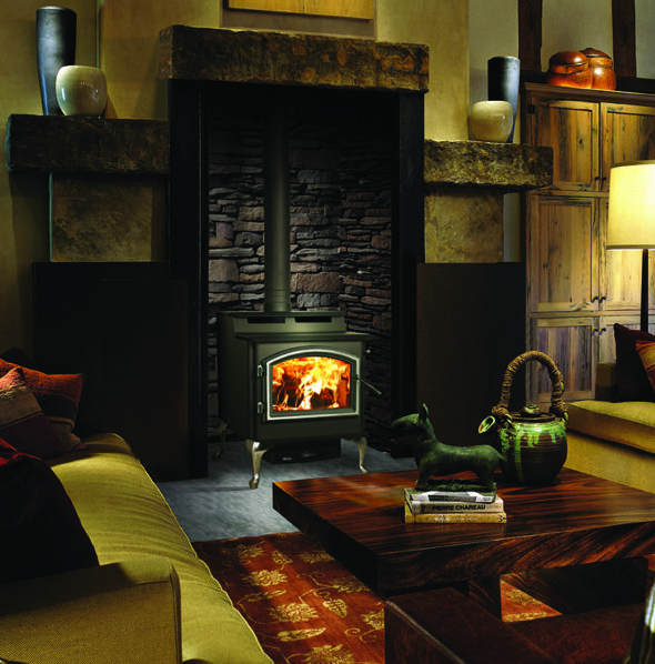 5700 Millennium step top wood stove by Quadra-Fire against a gray stone masonry wall in a living room