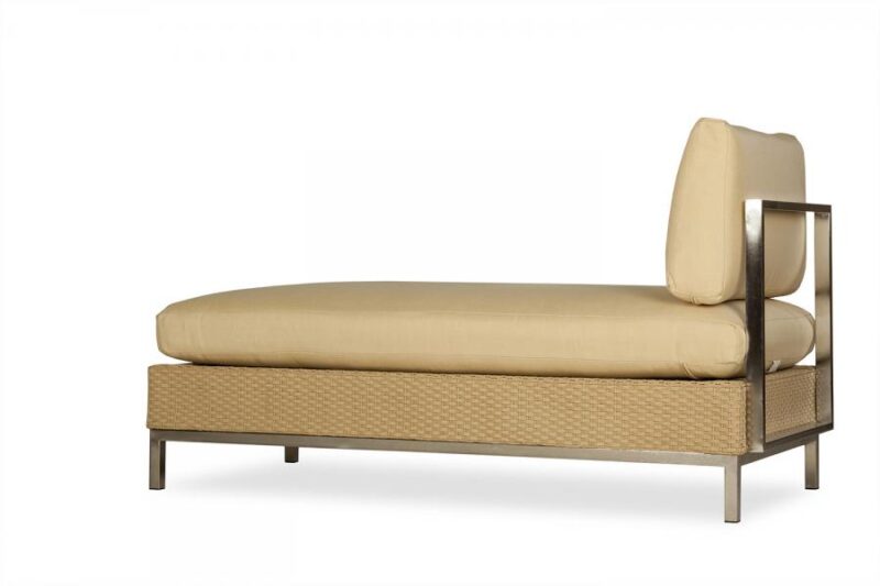 A modern single daybed with a beige mattress, a matching head cushion, and a tan wicker base set against a white background, positioned near an elegant fireplace.