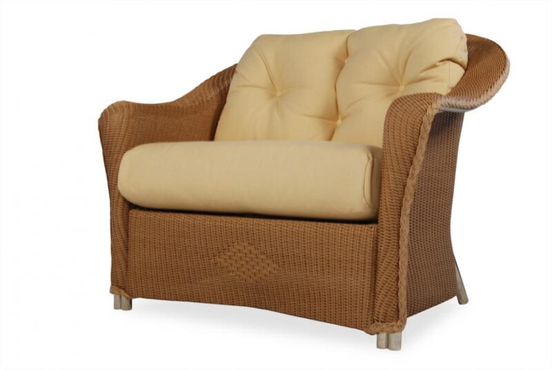 A comfortable wicker armchair with plush, cream-colored cushions and a cozy fire pit insert isolated on a white background.
