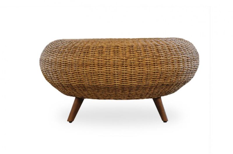 Woven wicker ottoman with a rounded, oval shape, standing on three angled wooden legs, designed as a cozy insert for fireplace areas, isolated on a white background.