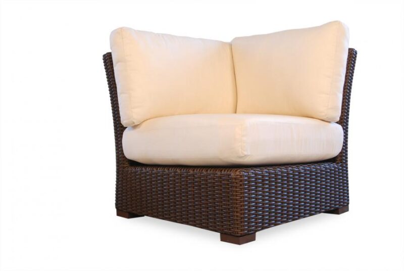 A brown wicker corner chair with plush, off-white cushions against a plain white background and a fire pit insert.