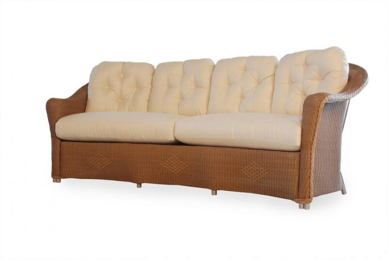 An elegant wicker sofa with a tufted backrest and smooth cream cushions, isolated on a white background, near a cozy fireplace.