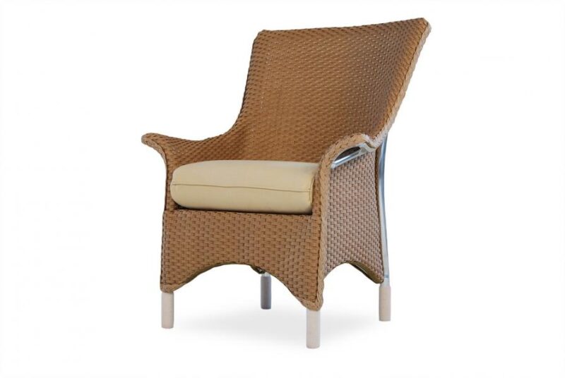 A modern wicker armchair with a high back, featuring beige cushioning near a fireplace on a white background.