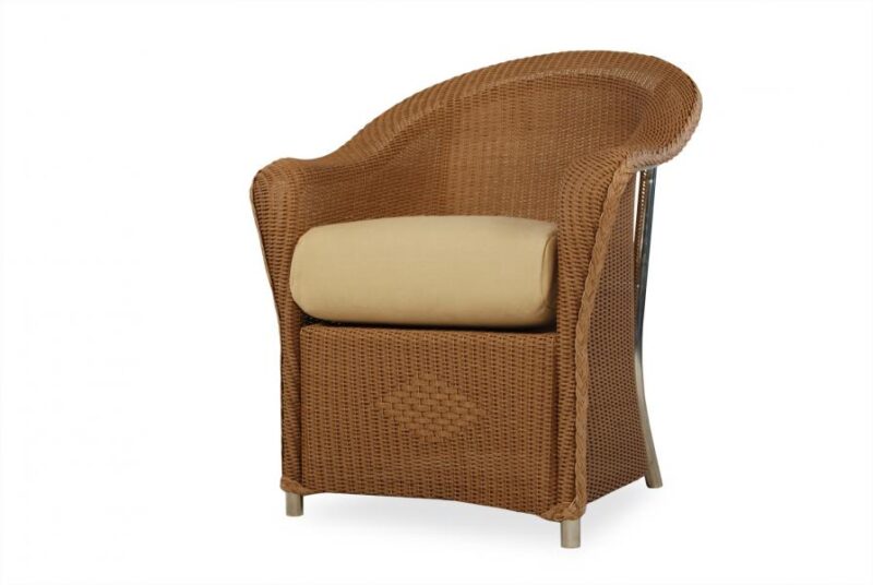 A wicker armchair with a curved back and a beige cushion near a fireplace, set against a white background.