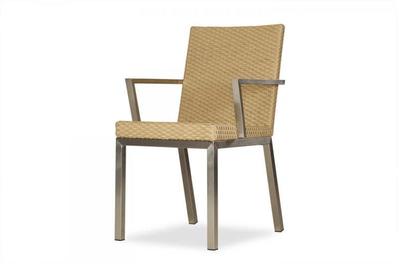 A modern chair with a metallic frame and woven beige seat and backrest, positioned against a plain, light background near a fireplace.