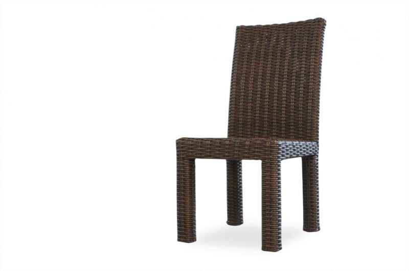 A tall, slender wicker chair with a high back, crafted from dark brown intertwined wicker strands, isolated on a white background near a fireplace.