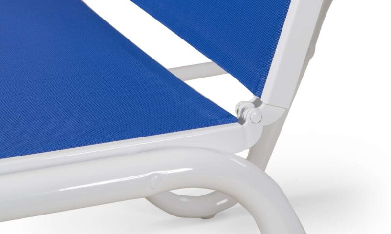 Close-up of a white-framed chair with a vibrant blue fabric seat and backrest, highlighting the joint detail and structure by a fireplace.
