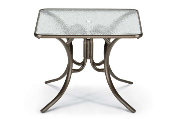 A small square table with a textured glass top and an ornate metallic bronze base featuring curved legs, insert isolated on a white background.