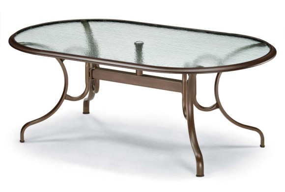 An elegant oval glass-top coffee table with a metal frame featuring graceful, curving legs. The table has a classic, refined design ideal for a sophisticated interior decor near the fireplace.