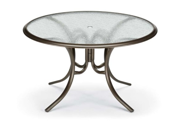 Round glass-top table with a metal frame on a white background. The table's legs are curved and symmetrical, giving it a stable and elegant appearance with an insert design.
