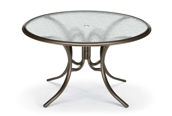 Round glass top table with a metallic bronze frame and a stove insert on a white background.