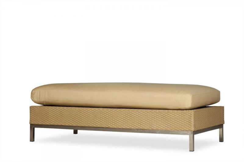 A modern outdoor daybed with a tan cushion on a metal frame with a woven base and an insert fireplace, isolated on a white background.