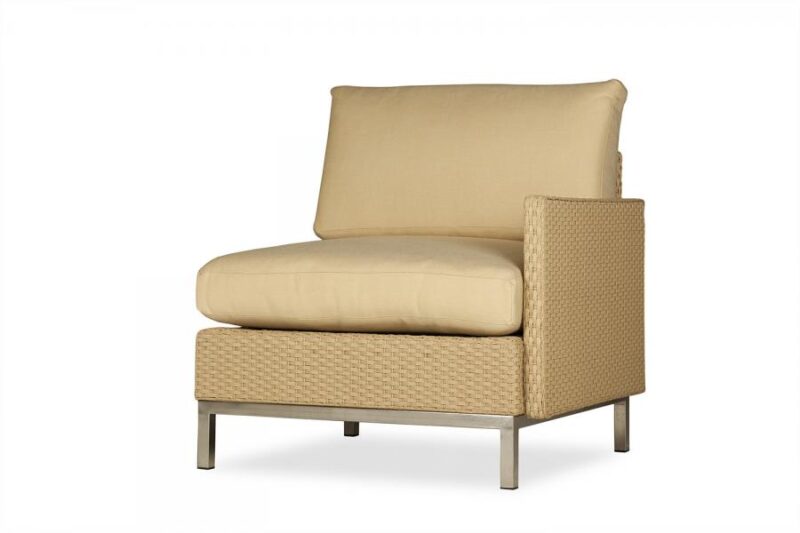 A modern beige armless chair with a large cushion and a woven side frame supported by a sleek metallic base, isolated on a white background with a fire pit insert.