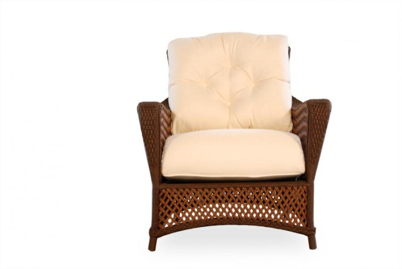A cozy wicker armchair with plush, cream-colored cushions, set beside a warm fireplace against a plain white background.