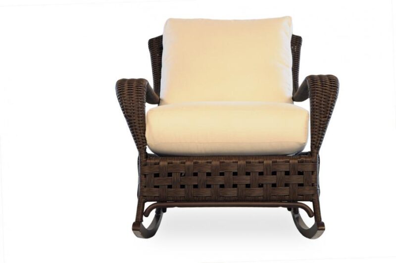 A cozy wicker rocking chair with a plush cream cushion and a matching headrest, set against a plain white background, ideal for relaxing beside a fire pit.