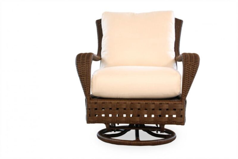 A brown wicker swivel chair with a plush beige cushion set against a white background by a cozy fireplace.