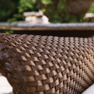 Close-up of a textured wicker basket showing intricate weaving patterns, with a blurred background of a fire pit.