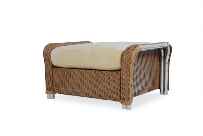A brown wicker ottoman with a beige cushion on top, set against a white background. The ottoman features a sturdy, woven design with visible legs and an insert for additional comfort.