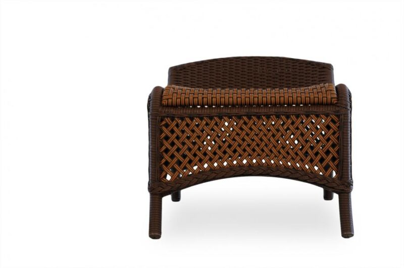 A brown wicker chair with an intricate weave pattern and rounded arms, displayed against a white background near a fireplace.