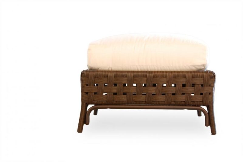 A modern wicker ottoman with a plush, white cushion, set against a white fire pit background.