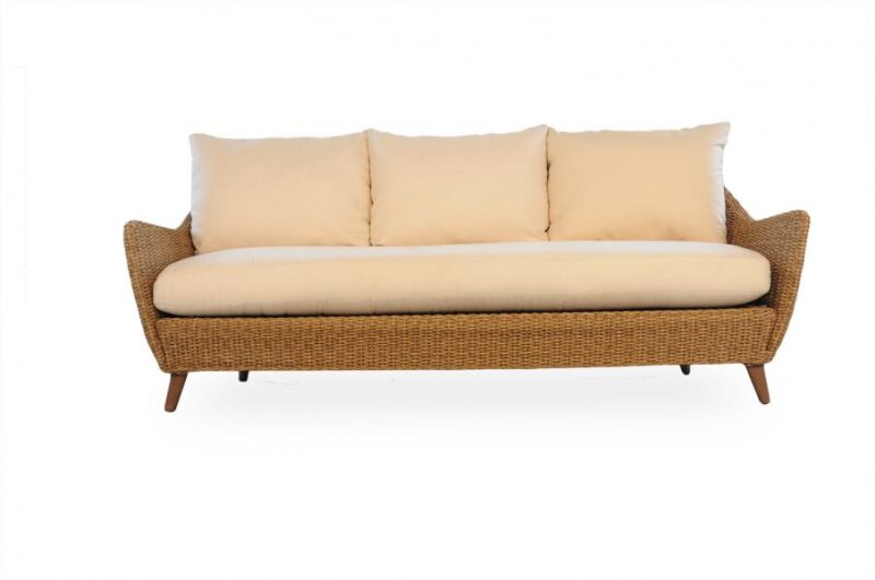 A beige upholstered sofa with a woven base and angled wooden legs, displayed against a fireplace backdrop.