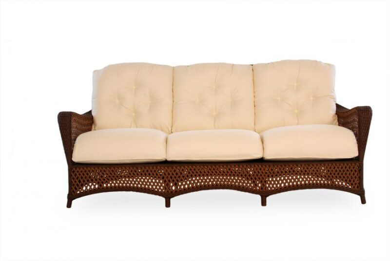 A rattan sofa with a curved frame and cream upholstered cushions, isolated on a white background, perfect for pairing with a fire pit.