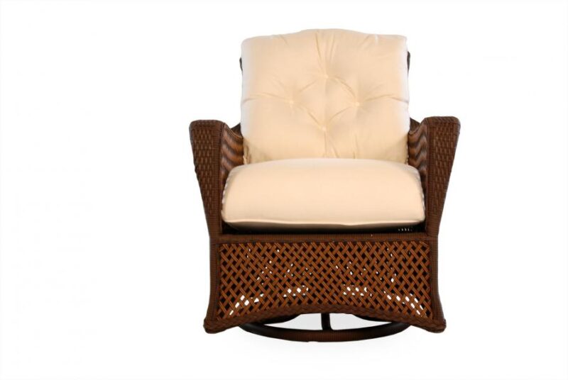 An elegant brown wicker armchair with plush white cushions, presented against a white background near a cozy fireplace.
