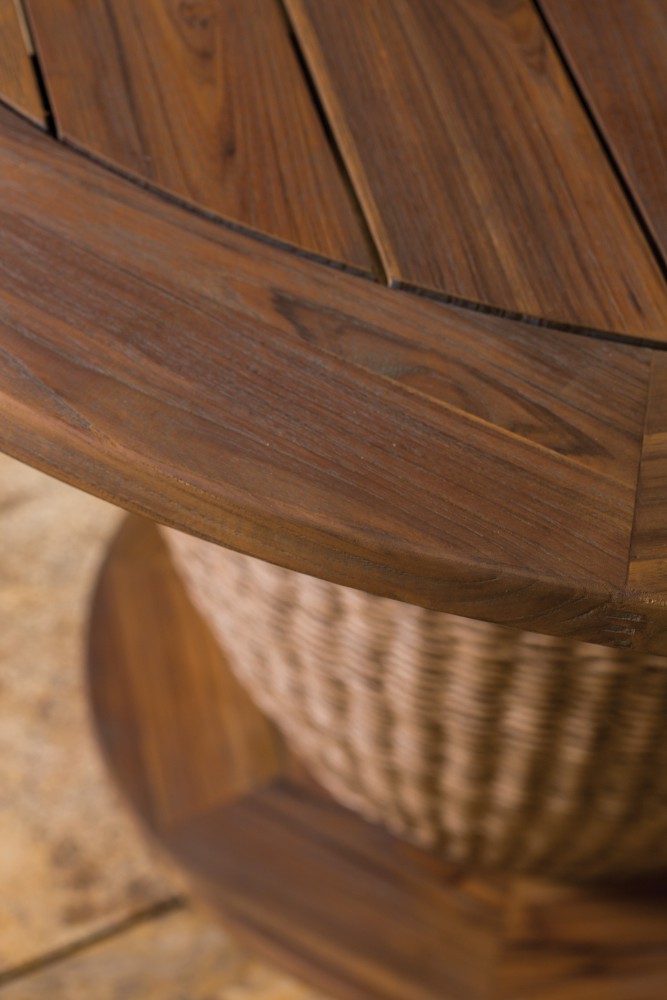 Close-up of wooden slats curving around a spherical wicker base, showcasing detailed wood grain and natural textures with a warm, soft focus background near a fire pit.