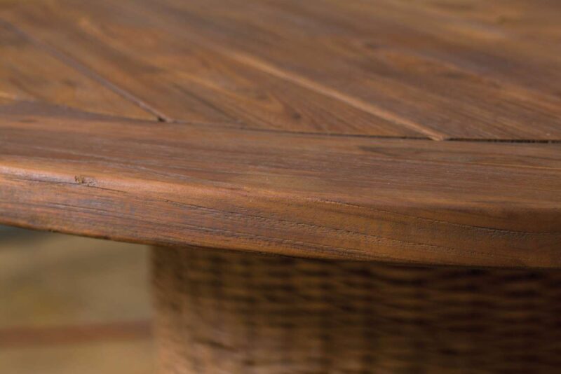 Close-up of a wooden table showing detailed wood grain and texture, with a focus on the smooth, rounded edge. The table has a rich, warm brown finish and features an elegant fireplace insert in its