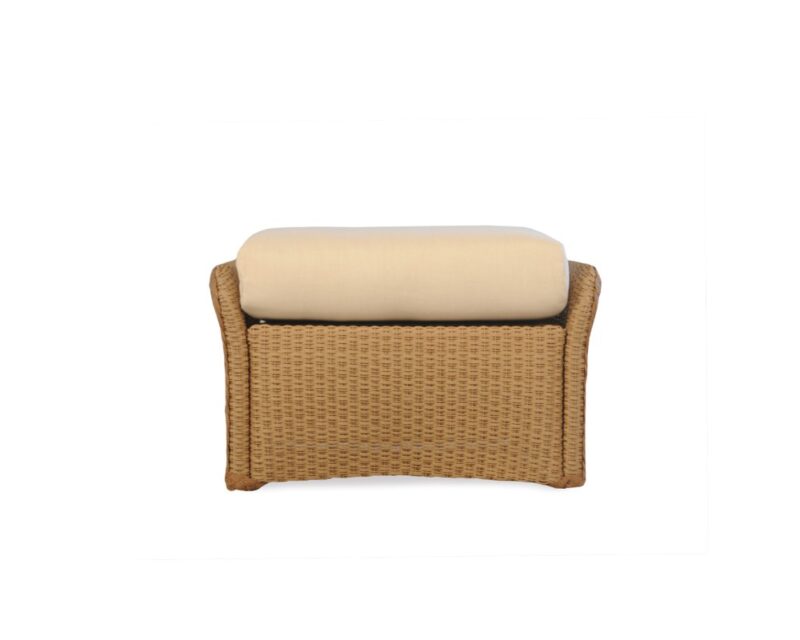 A modern wicker stool featuring a natural brown weave and a thick, cushioned top upholstered in off-white fabric, isolated on a white background with a fire pit insert.