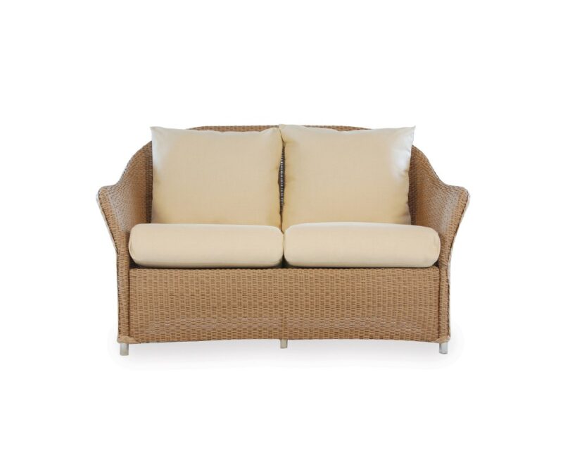 A modern wicker loveseat with a beige cushion and two matching square pillows, isolated on a white background, ideal for pairing with a fire pit.