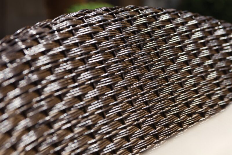 Close-up of a textured fabric with a detailed, woven pattern in shades of brown and black, highlighted under the bright light of a fire pit.