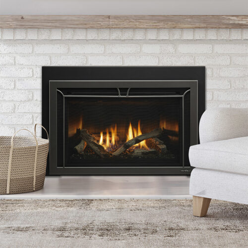 Cosmo gas fireplace insert by Heat & Glo in graphite with Iron Age front against a white brick hearth