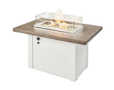 A rectangular outdoor fire pit table with a glass wind guard around the flame, featuring a wood and white panel design, and a storage door.