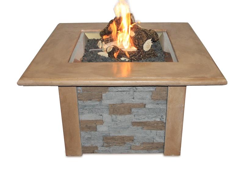 A square outdoor fireplace table with a beige concrete top and stone veneer sides, featuring a vibrant flame burning over decorative rocks.
