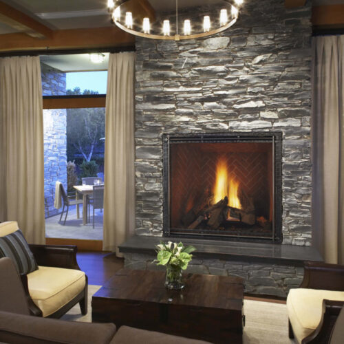 TRUE 42 inch gas fireplace by Heat & Glo in black with Forge front against a gray stone masonry hearth
