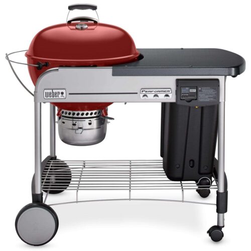 A Weber Performer Deluxe Crimson Grill featuring a silver work table, storage rack, and wheels for mobility.
