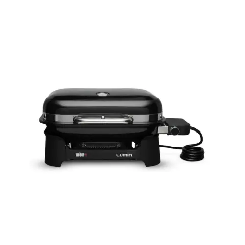 A black weber lumin electric grill with a closed lid, positioned on a stand with visible controls and a connected power cord.