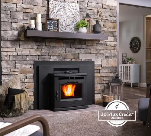 A cozy living room featuring a modern wood-burning stove with visible flames, set against a stone wall. a wooden shelf above displays decorative items. a stamp in the corner indicates a 30% tax credit qualification.