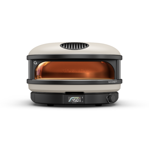 A gozney dome outdoor pizza oven in silver and black, displaying a temperature of 450°f, with visible flames inside.